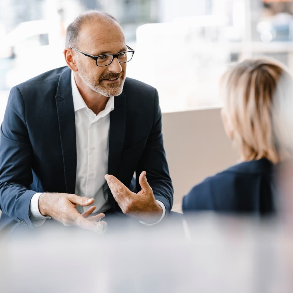 Businessman and woman having a meeting in a coffee shop, discussing work.