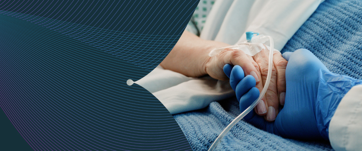 Healthcare provider and cancer patient holding hands while the patient is in the hospital.