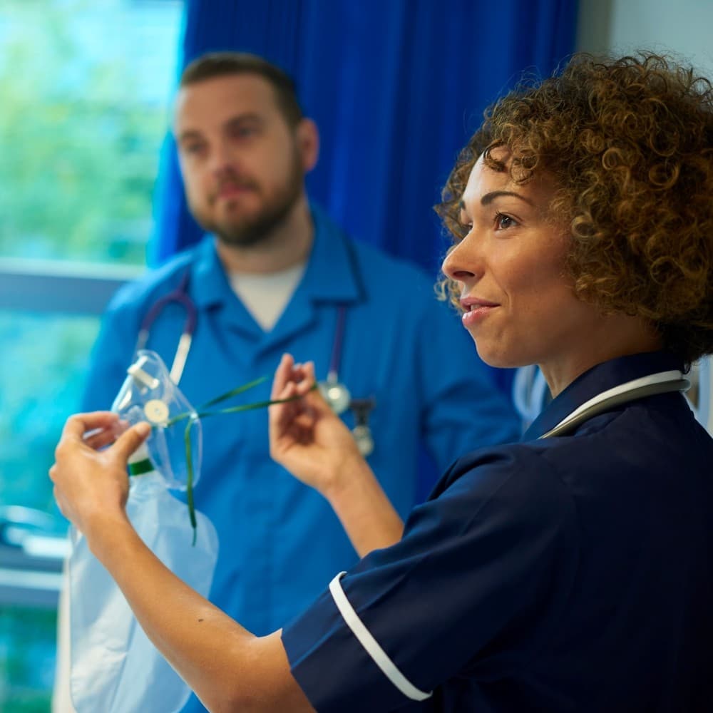 Research nurse demonstrating medical equipment usage to other staff.