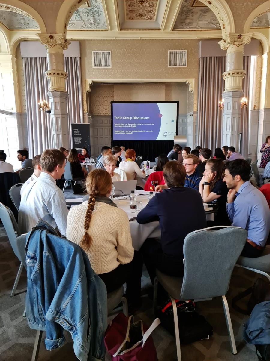 Photo of delegates round tables at the 2022 ECMC JING: Training the Next Generation event